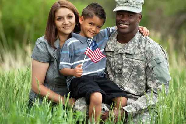 A us military soldier sitting with his son and his wife posing for a photo